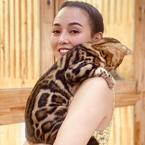 Người phụ nữ bế chú mèo Bengal với bộ lông da báo độc đáo trên vai.