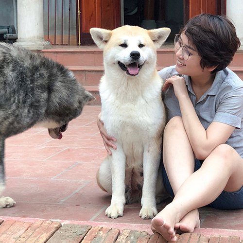 Chó Akita Inu trưởng thành ngồi cạnh người chủ, dáng vẻ thân thiện và hạnh phúc