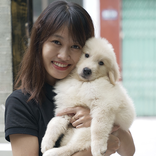Người phụ nữ bế chó Golden Retriever con lông trắng kem