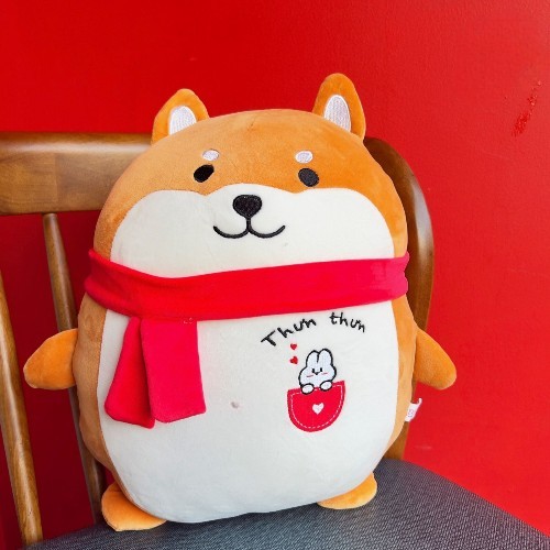 Gấu bông chó Shiba Miniso đáng yêu với khăn quàng đỏ, ngồi trên ghế gỗ, làm món quà ý nghĩa.